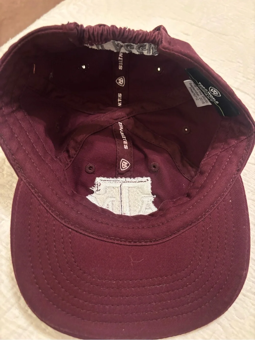 A&M baby baseball cap, elastic back w/ white embroidered A&M Logo & Lil’Aggie